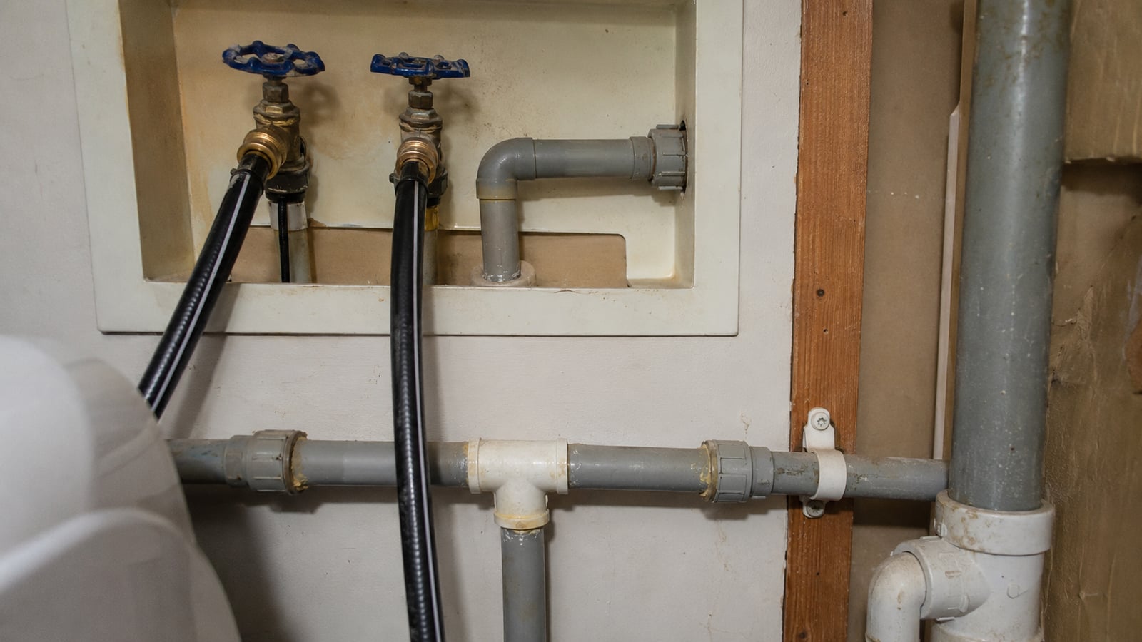 Aging polybutylene plumbing pipe visible inside a 1990s-era home utility area