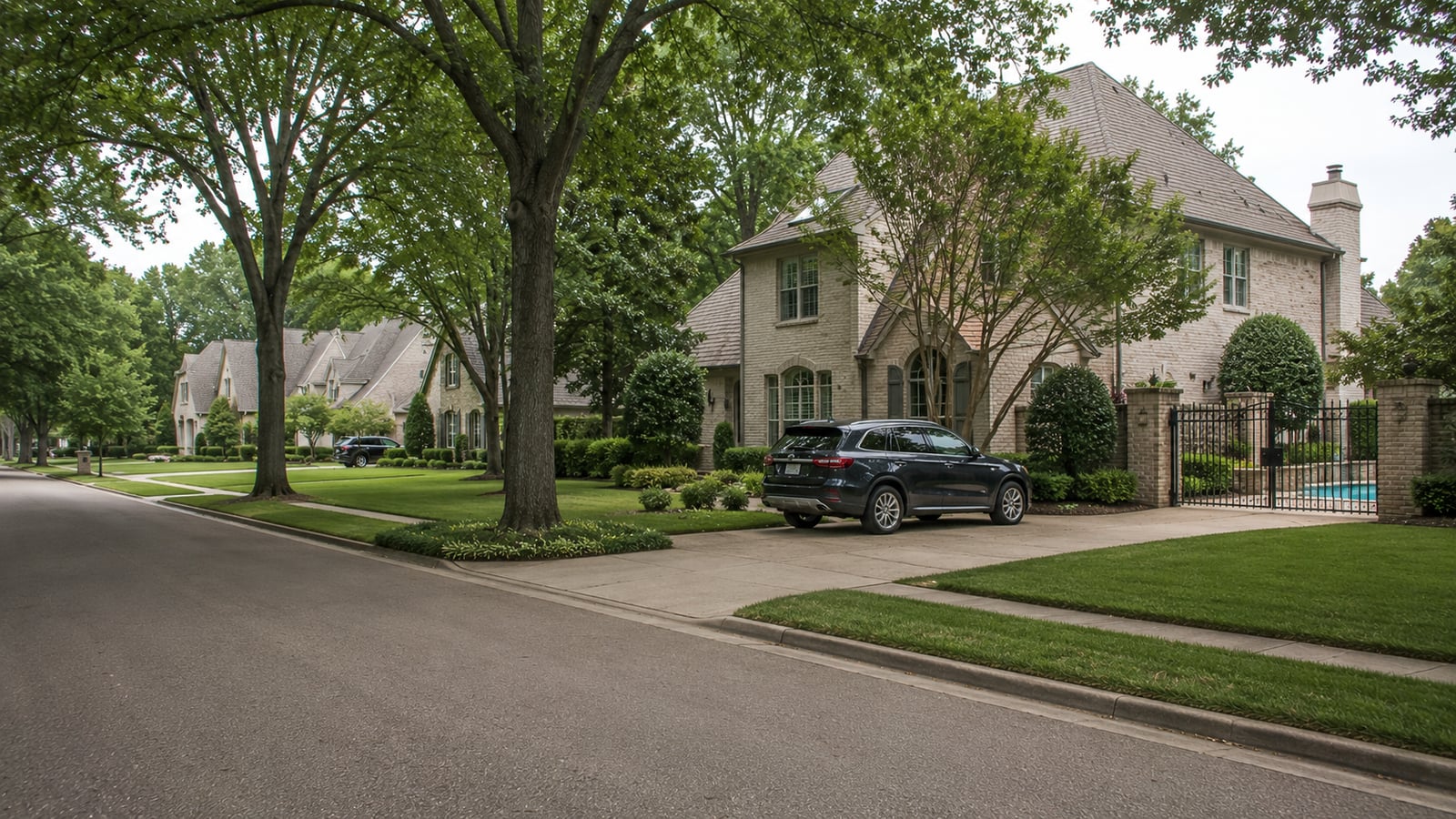 Established Germantown Tennessee residential street showing large custom homes with mature landscaping and an in-ground pool visible through a side gate