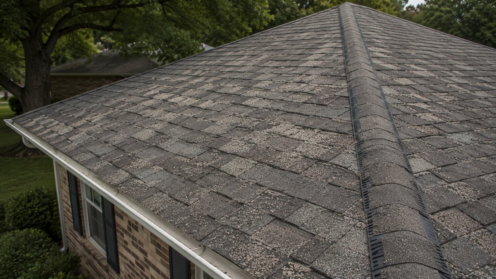 Aging asphalt shingle roof on a ranch-style home in an established Tennessee suburb showing weathering consistent with older construction