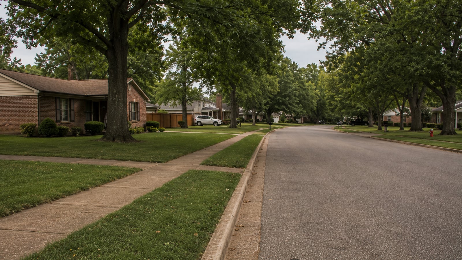 Quiet residential street in established Bartlett Tennessee neighborhood showing late 1970s and 1980s ranch and split-level homes with mature tree canopy
